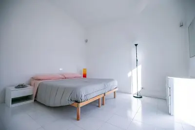 a bedroom with a bed with pink sheets and a refrigerator at Casa Maia in Sanzeno
