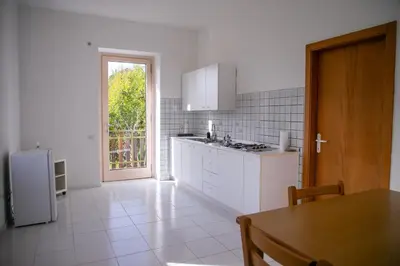 a white kitchen with a table and a refrigerator at Casa Maia in Sanzeno