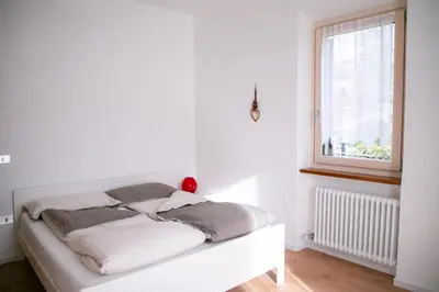 a bed in a white room with a window at Casa Maia in Sanzeno