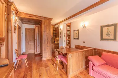 a home office with a wooden desk and pink chairs at Casa Crignes, residenziale a due passi dal centro in Cortina dʼAmpezzo