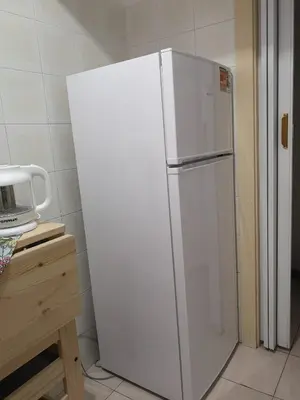 a white refrigerator in a kitchen next to a table at Nido del Melo in Cles