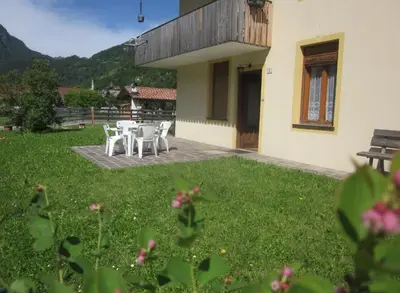 a patio with white tables and chairs in a yard at Casa Dolomite in Mezzano