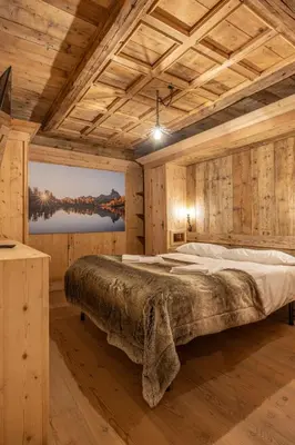 a large bed in a room with wooden walls at Casa Aquila, con sauna privata in Chiave