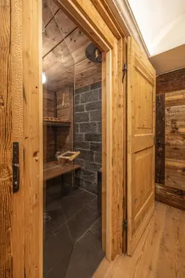 a bathroom with a wooden door and a stone wall at Casa Aquila, con sauna privata in Chiave