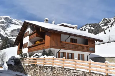 a house covered in snow with a fence in front at Chalet Pradat in Arabba