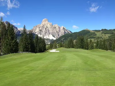 a golf course with a mountain in the background at Chalet Pradat in Arabba