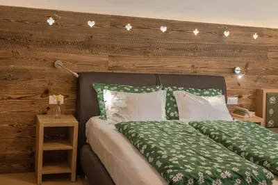 a bedroom with a bed with green and white sheets at Chalet Pradat in Arabba