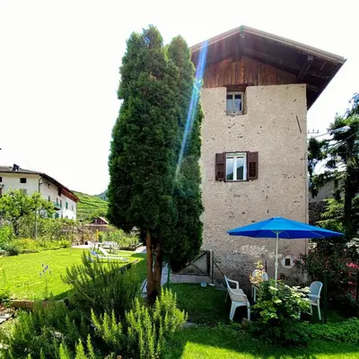 a building with a tree and a blue umbrella at El Me Popo in Segonzano