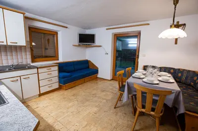 a living room with a table and a blue couch at Gatscherhof Retreat - Family Appartement in Chienes