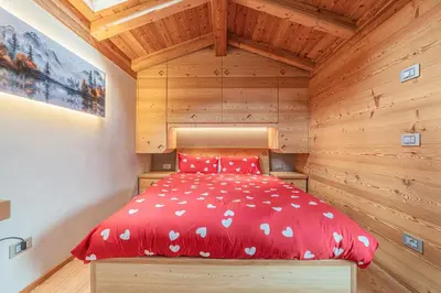 a bedroom with a red bed and a window at The Love Chalet in Falcade