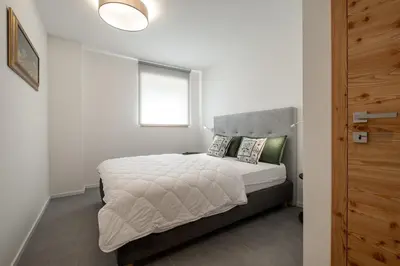 a bedroom with a bed with white sheets and a window at Cèsa Cercenà in Canazei