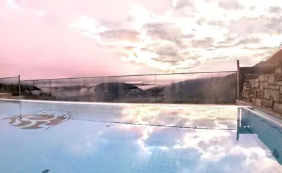 a swimming pool with a cloudy sky in the background at Bärenhotel in Valdaora