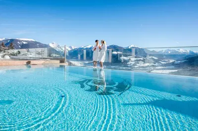 two women standing on the edge of a swimming pool at Bärenhotel in Valdaora