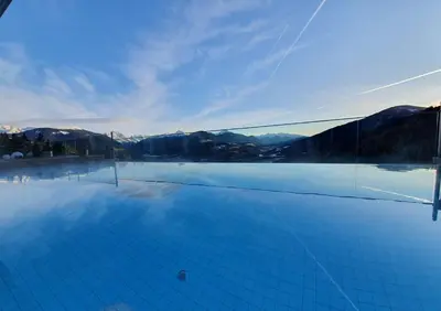 a view of a swimming pool with mountains in the background at Bärenhotel in Valdaora