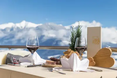 a table with two glasses of wine on top of a mountain at Bärenhotel in Valdaora
