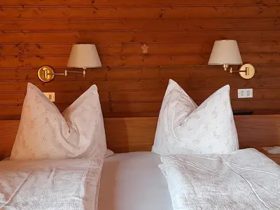 a bed with white pillows and two lights on it at Appartament Alpenheim in Ferrara