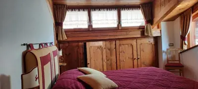 a bedroom with a purple bed and a window at Casa Falco in Cortina dʼAmpezzo