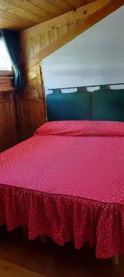 a bedroom with a bed with a red bedspread at Casa Falco in Cortina dʼAmpezzo