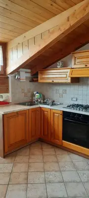 a kitchen with wooden cabinets and a black stove at Casa Falco in Cortina dʼAmpezzo