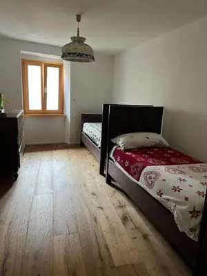 a bedroom with a bed and a wooden floor at Ciasa dei Pomi Apartment in Sfruz