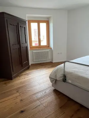 an empty bedroom with a bed and a window at Ciasa dei Pomi Apartment in Sfruz