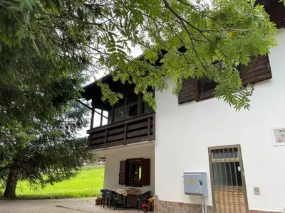 a white building with a balcony and a table at Ca' Virginia - Val di Fassa in Vigo di Fassa