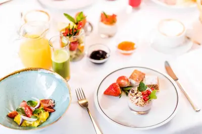 a white table with plates of food and drinks at Hotel Rommisa in Perca