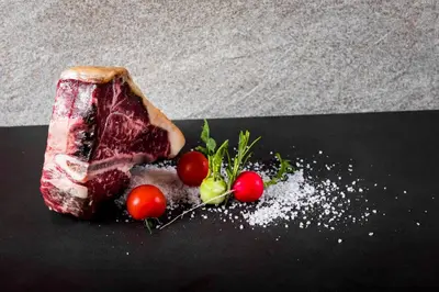 a piece of meat and some tomatoes on a table at Hotel Rommisa in Perca