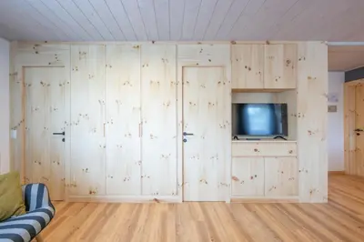 a living room with wooden walls and a tv at Mountain Vibes Colfosco in Colfosco