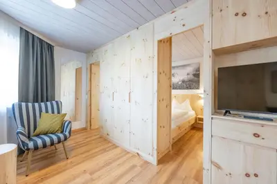 a room with a bed and a tv and a chair at Mountain Vibes Colfosco in Colfosco