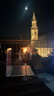 a laptop and a glass of wine on a table at Sunflower House in Bolzano