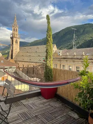 a balcony with a hammock and a building with a clock tower at Sunflower House in Bolzano