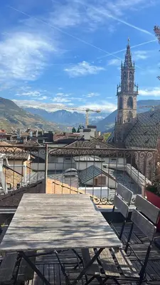 a table and chairs on a balcony with a clock tower at Sunflower House in Bolzano