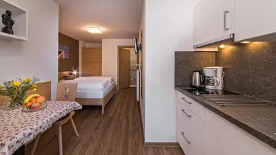 a kitchen with a table and a bed in a room at Appartement Treffpunkt in Molini di Tures