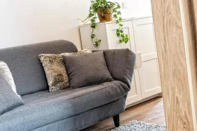 a gray couch with pillows in a living room at Appartement Treffpunkt in Molini di Tures