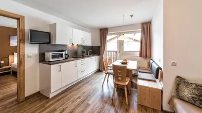 a kitchen and living room with a table and a microwave at Appartement Treffpunkt in Molini di Tures