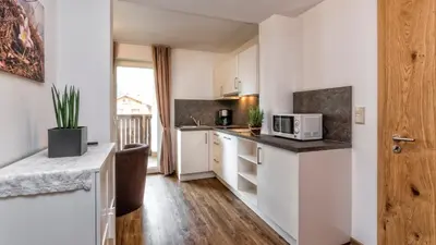 a small kitchen with white cabinets and a microwave at Appartement Treffpunkt in Molini di Tures