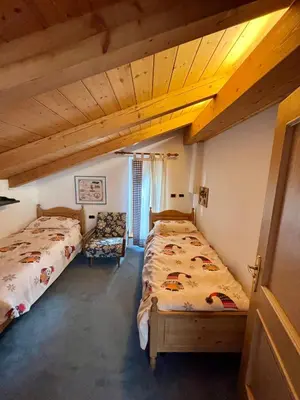 a bedroom with two beds and a chair at Pragma Apartments - Casa Defrancesco in Cavalese