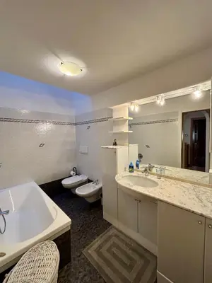 a bathroom with a tub and a sink and two toilets at Pragma Apartments - Casa Defrancesco in Cavalese
