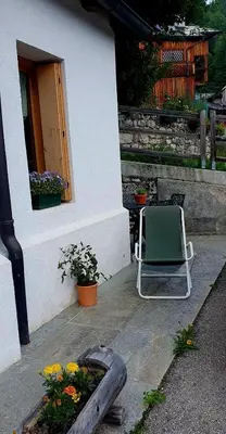 a chair sitting outside of a house with flowers at Sunny and cosy holiday apartment in the Dolomites in Pianaz