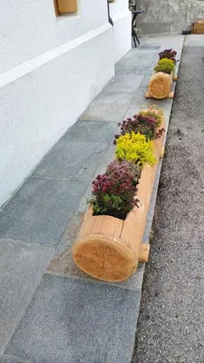 three wooden planters with flowers on a sidewalk at Sunny and cosy holiday apartment in the Dolomites in Pianaz