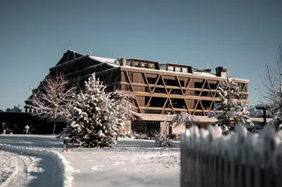 a house in the snow with a mountain in the background at Green Luxury Hotel Pfösl in Nova Ponente