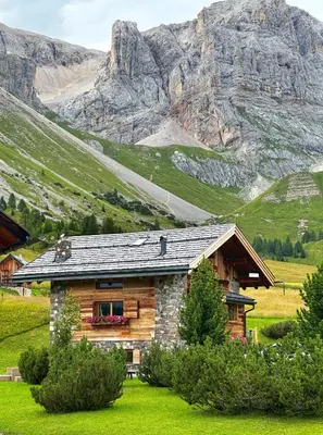 a log cabin in front of a mountain at Suite Chalet Stella Margherita in Passo San Pellegrino