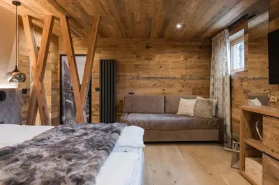 a bedroom with a bed and a couch in a room at Suite Chalet Stella Margherita in Passo San Pellegrino