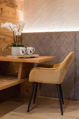 a wooden table with a chair and flowers on it at Suite Chalet Stella Margherita in Passo San Pellegrino