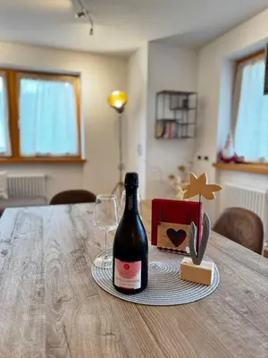 a bottle of wine and a glass on a table at Appartamento La Finestra sul Pelmo in San Vito di Cadore