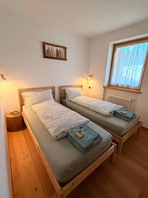 two twin beds in a room with a window at Appartamento La Finestra sul Pelmo in San Vito di Cadore
