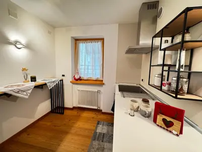 a kitchen with a white counter and a window at Appartamento La Finestra sul Pelmo in San Vito di Cadore