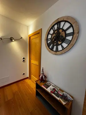 a room with a clock on the wall and a table at Appartamento La Finestra sul Pelmo in San Vito di Cadore