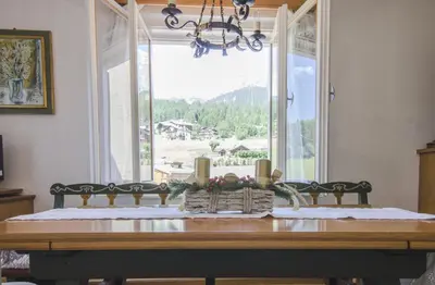 a dining room table with a view of a window at Casa Ronco in Cortina dʼAmpezzo